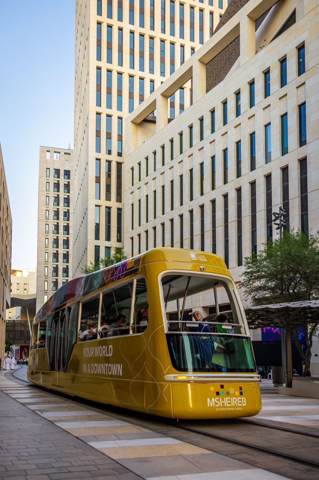 The gold Msheireb tram curving through Downtown Doha