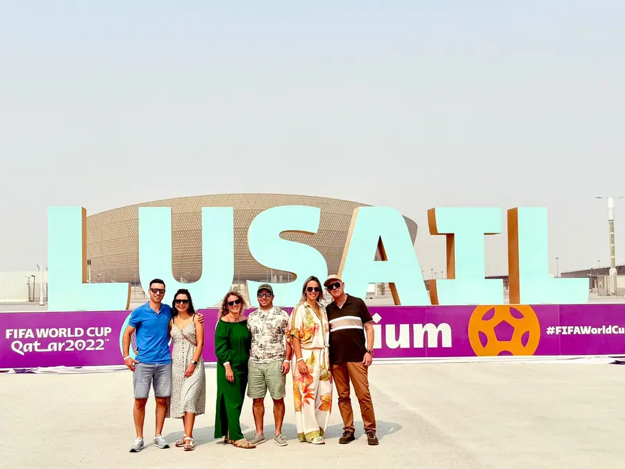 A group gathered at the Lusail Stadium sign