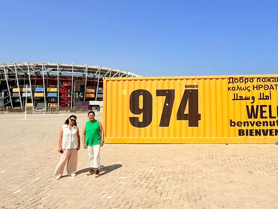 Two guests at the multilingual welcome container outside Stadium 974